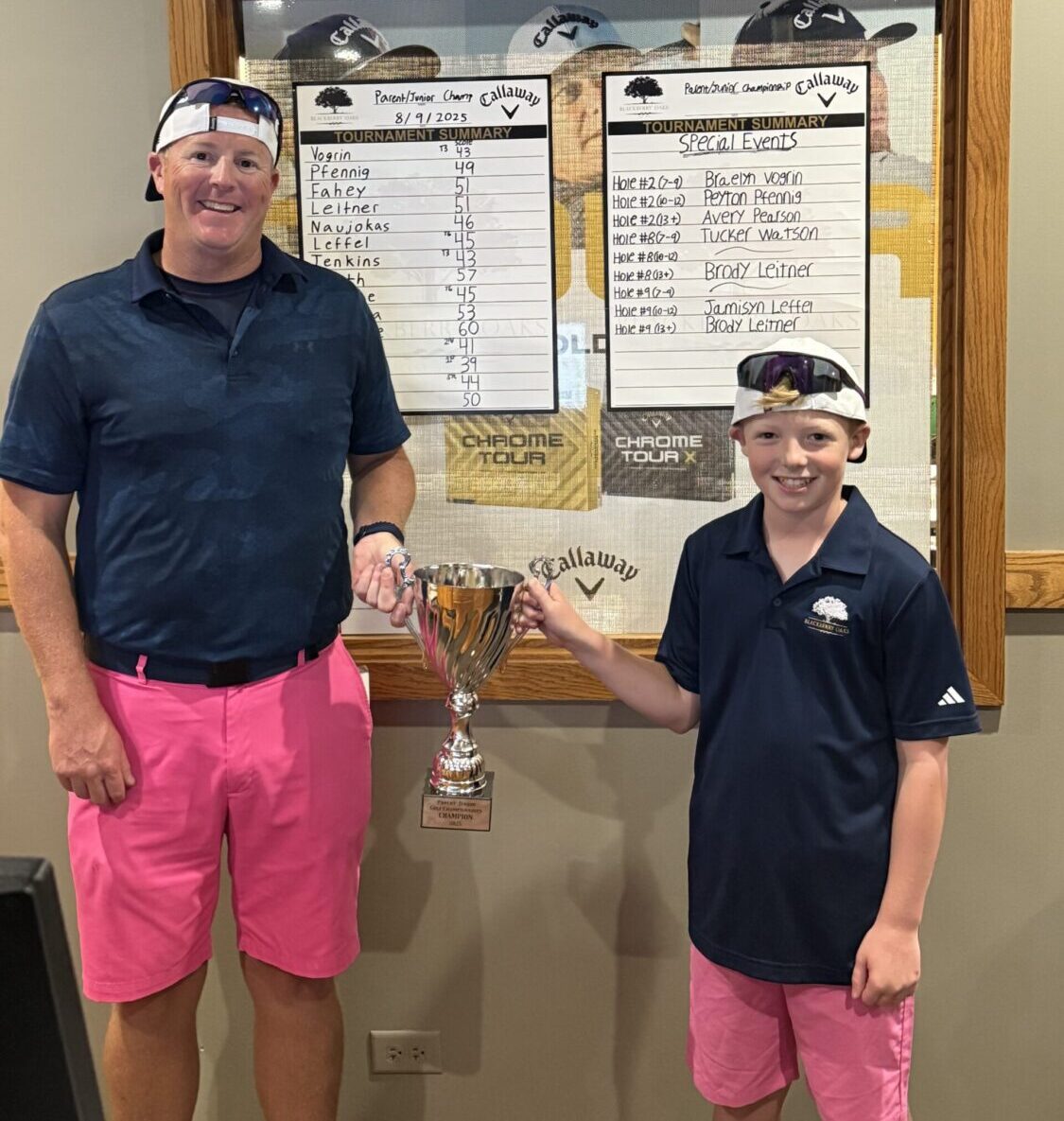 Two golfers holding tournament trophy