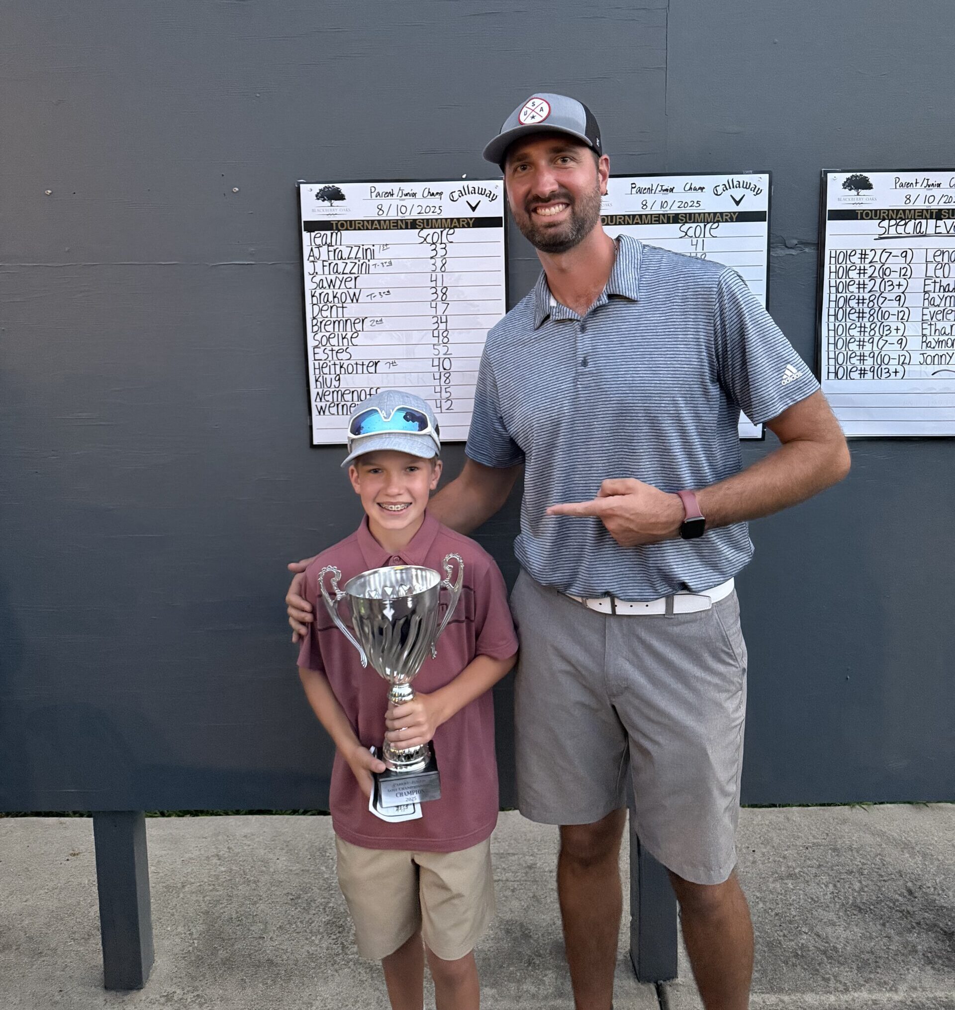 Young boy holding trophy with smiling man